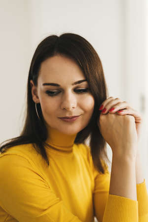 Portrait of a young woman with dark hair wearing yellow turtleneck sweaterの写真素材