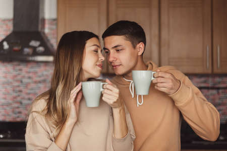 Couple drinking morning coffee together at the kitchen. Moment of togetherness. Love and relationship conceptの写真素材
