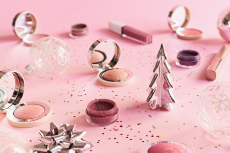 Makeup products on pink background. Christmas or New Year party makeup cosmetics. Blushes, eyeshadow and lip glossの写真素材