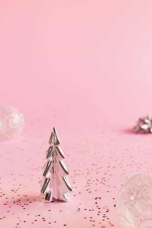 Minimal Christmas background of pink color: small Christmass tree, transparent balls and colorful confettiの写真素材