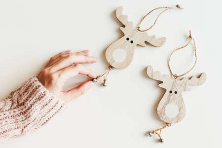 Hand holding wooden Christmas ornaments, white background. Eco friendly handmade deer shaped Christmas decorの写真素材