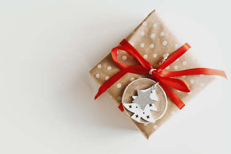 Christmas gift box wrapped in polka dot kraft paper decorated with red ribbon and wooden Christmas tree and star shaped ornament. Eco friendly gift wrapping ideaの写真素材