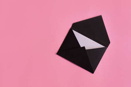Black envelope with paper card on pastel pink background. Invitation, greeting card, letter or wish list conceptの写真素材