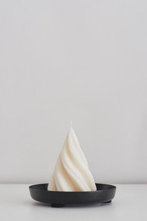 Spiral cone soy wax candle on a black metal tray. Handmade candle for home decorの写真素材
