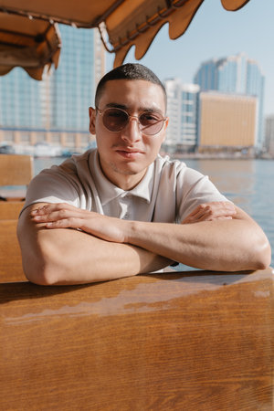 Portrait of a young male tourist taking a ride on abra boat. Generation Z arab man. Solo taveler...