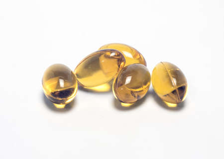 Yellow vitamin pills on a white background
