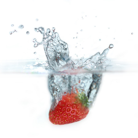 fresh strawberry dropped into water on white backgroundsの写真素材