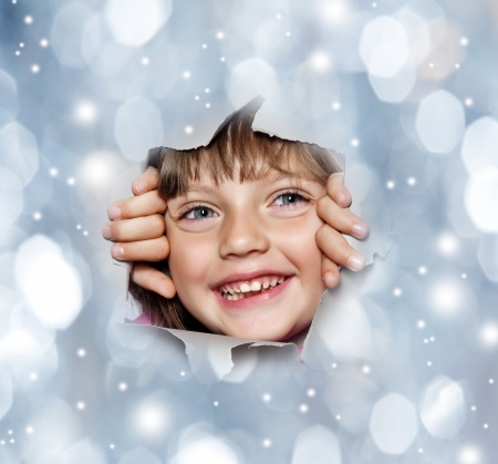 happy little girl looking out of a hole in christmas backgroundの写真素材