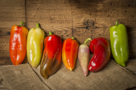 red, green and yellow bell peppers on a kitchen wooden tableの写真素材