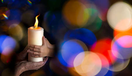 old hands and baby hands holding a candle - concept