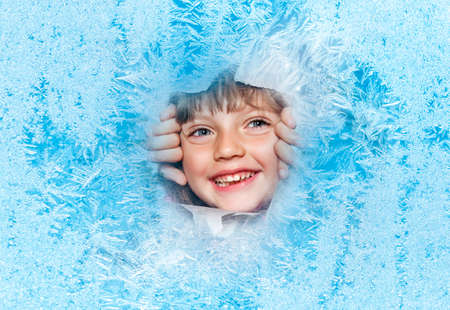 happy little girl looking out of a hole in christmas backgroundの写真素材