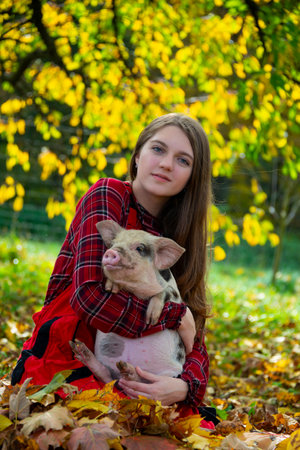 a happy farmer girl with a little piglet (kune kune)の写真素材