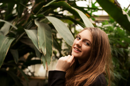Portrait of happy beautiful young science student. Youn girl in a greenhouse with tropic plantsの写真素材