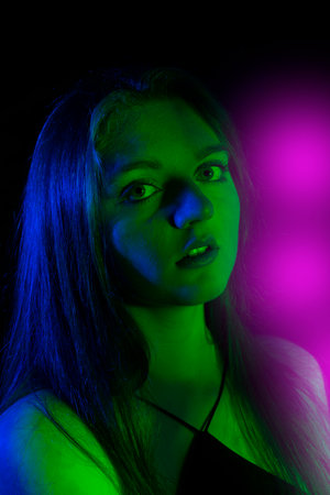 face of girl on a dark background with colored lights - art portraitの写真素材