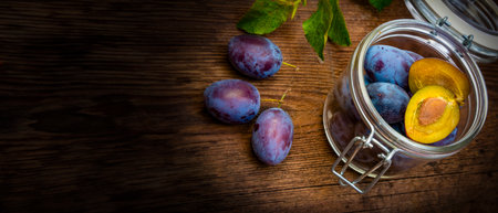 plums in a bottle on a wooden tableの写真素材