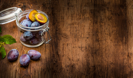 plums in a bottle on a wooden tableの写真素材