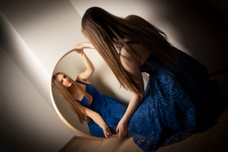 young woman looks in the mirror - art photoの写真素材