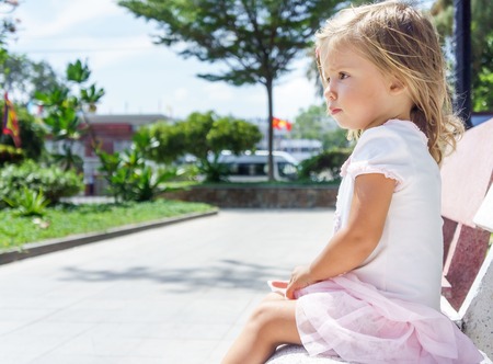beautiful little girl sitting on the bench.の写真素材