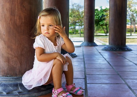 little girl sitting near the column.の写真素材