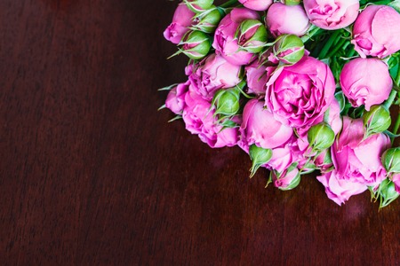 bouquet of beautiful pink peonies, roses with green leaves lie on a wooden table.の写真素材