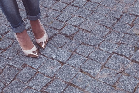 female legs in a beautiful peach high-heeled shoes with gold nose. close-up. on the granite pavement.の写真素材