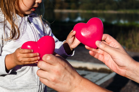 man's hand holds baby Two red plastic heart.の写真素材