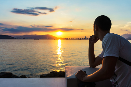 Young man is looking at the sunrise.