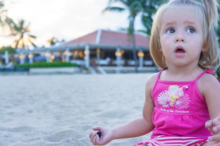 Baby girl playing on the beach. She opened her mouth in surprise.の写真素材