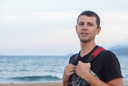 portrait of a handsome young man standing against a beach.の写真素材