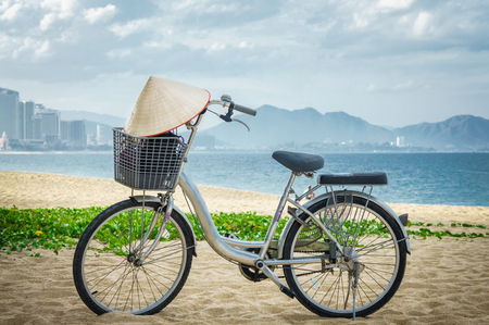 Bicycle parking in the beach sand. on bicycle handlebars Vietnamese hat hanging. Vietnam.の写真素材