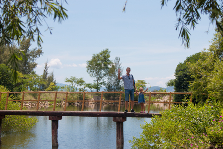 Happy father man with his little daughter walking across the wood sea bridgeの写真素材