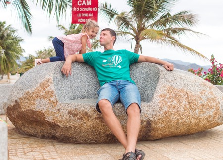 Happy father with a child sitting on the stone near the beach, they play and smile.の写真素材