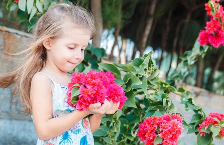 little girl is holding beautiful pink flowers. bougainvilleaの写真素材