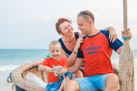 family in a boat with a paddle on the beach.の写真素材