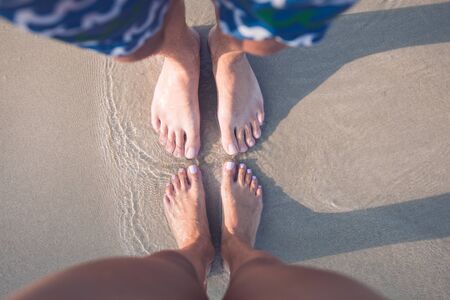 male and female feet on the sand