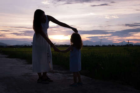 Young Mother and daugther play at night near rice field, nature, travel.の写真素材