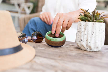 white flowers, bracelet with charm, succulent in pot on the wood table. woman hands. Close up, copy spaceの写真素材