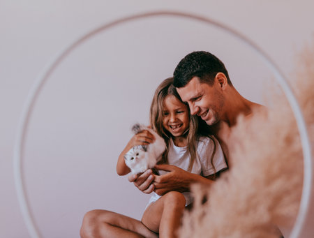 Happy affectionate loving single father and cute small child daughter bonding embracing laughing sit on sofa.の写真素材