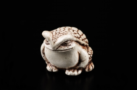 Netsuke toad on black background