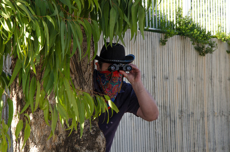 Cowboy in bandana looking through binoculars in ambush