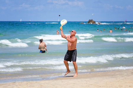 Bat Yam, Israel - September 6, 2014: Mature man plays Matkot in the beach of Bat Yam city. Matkot is the national Israeli beach sport. It is similar to tennis.のeditorial素材