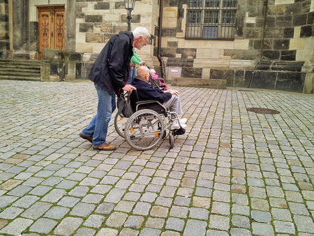 Dresden, Germany - September 30, 2014: Elderly woman in wheelchair is pushed by old man while touring in Dresden.のeditorial素材