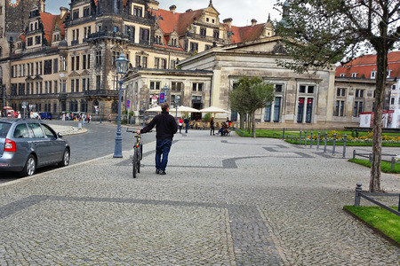 Dresden, Germany - September 30, 2014: Middle-aged man walks his bicycle down in the pavement of Theater Square.のeditorial素材