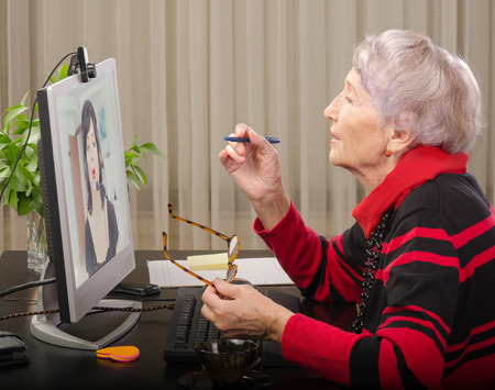 Grey haired expert is teaching online student how to sound like a native English speakerの写真素材