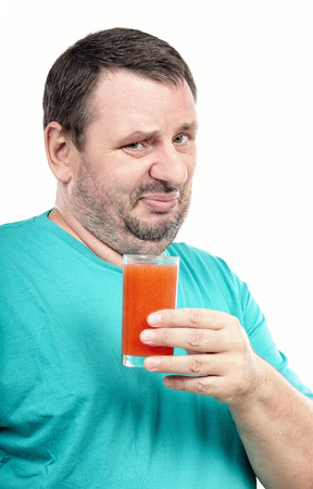 Middle aged discontented man is holding glass of detox drink on white backgroundの写真素材