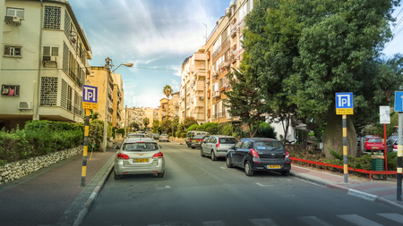 Rishon LeZion, Israel-February 18, 2016: View of Lilienblum Street from crosswalk at sunny bright day under blue sky. There are 3 and 4 story residential buildings, green tree and shrubs, parked cars in both sides. Horizontal shot.のeditorial素材