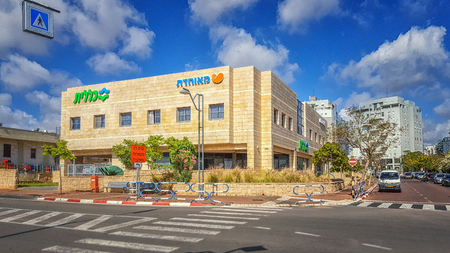 Rishon LeZion, Israel-April 14, 2016: Beautiful view of two-story yellow tiled building exterior with Hebrew letters flooded by sunset light under blue sky. There are two healthcare funds Meuhedet and Clalit. This service center is located at 8-10 Ha-Shirのeditorial素材