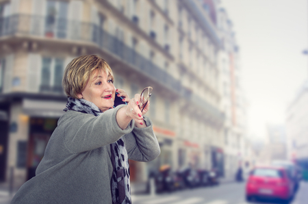 Lively mature adult business lady catching a taxi on blurred city street background. Horizontal shotの写真素材