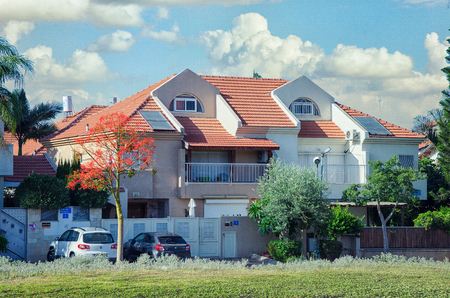 Rishon LeZion, Israel-June 10, 2017: Two-floor red roof private house of two separate living sections. The left section painted light brown the right one is white. Each section has a semi-recessed balcony with steel railing. There is a wide glass door to のeditorial素材