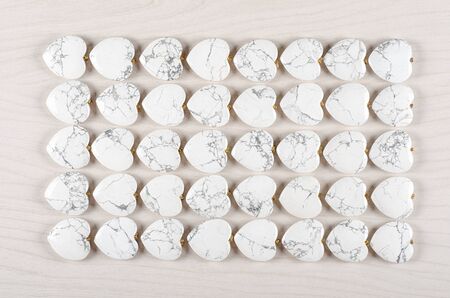 Forty white howlite heart-shaped stones are stowed five rows. Eight pieces in each one. Top view.の写真素材